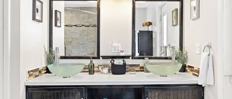 A bathroom with two glass sinks, a large mirror, and a dark wooden cabinet below.