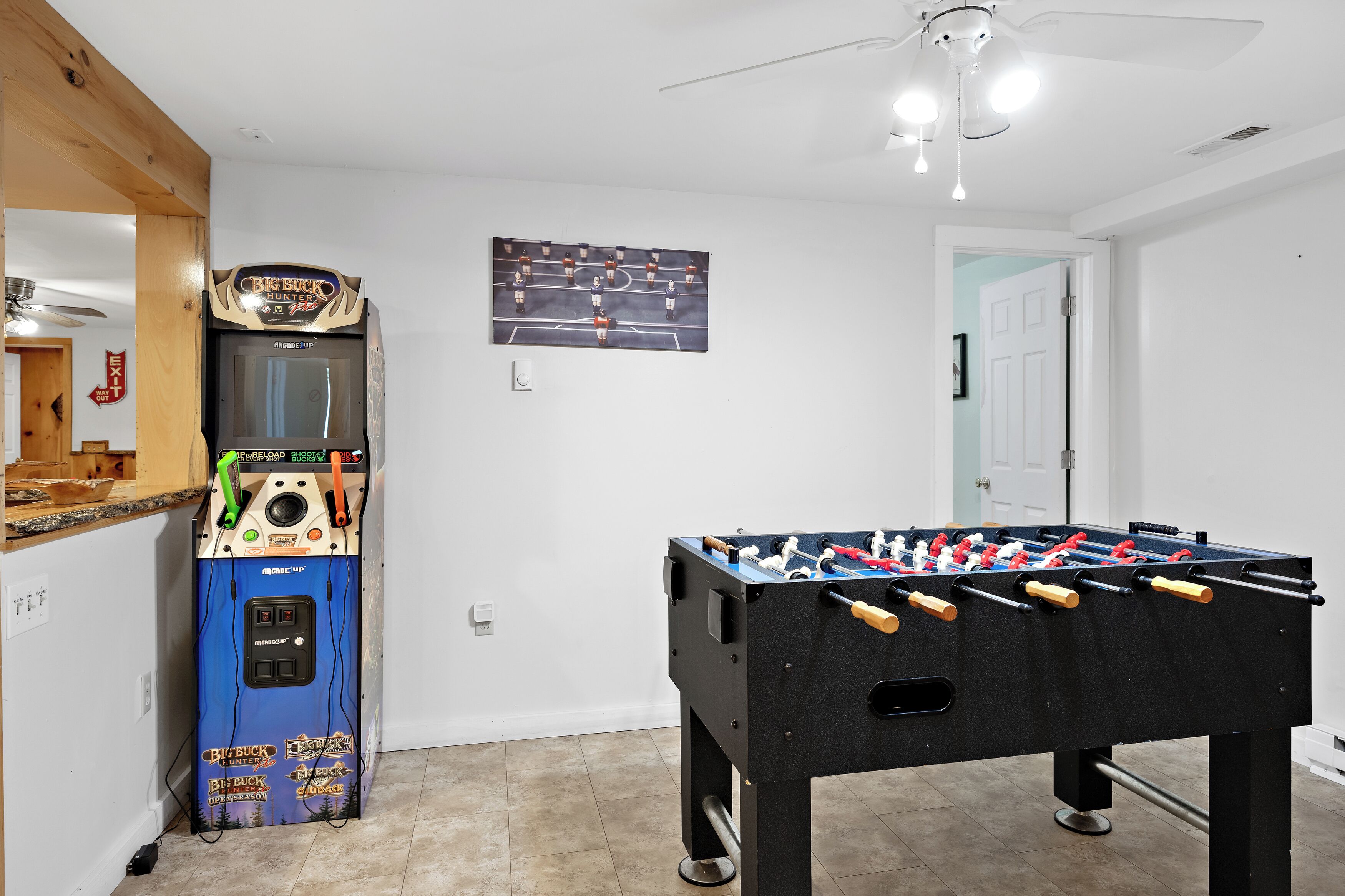 Una habitación con mesa de futbolín, juke box y televisor montado en la pared.