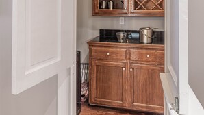 A compact kitchen with wooden cabinets, a wine rack, and a black countertop. - Garden District Upscale Escape w/Gated Off-St Parking & Streetcar Access (New Orleans)
