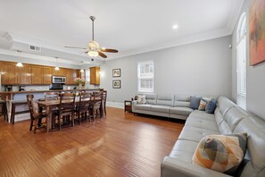 A modern living room with a dining area, a gray sofa, and wooden flooring.
