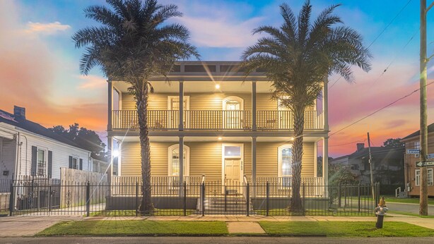 A two-story house with a balcony, a front porch, and a well-maintained lawn. - Garden District Upscale Escape w/Gated Off-St Parking & Streetcar Access (New Orleans)