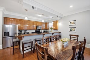 A modern kitchen with wooden cabinets, stainless steel appliances, and a dining area with a wooden table and chairs.