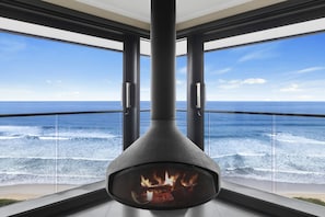 A modern interior with a fireplace and a view of the ocean.