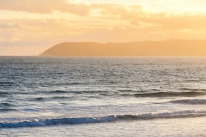 A coastal view with waves and a distant mountain range. - The Pole House (Fairhaven)