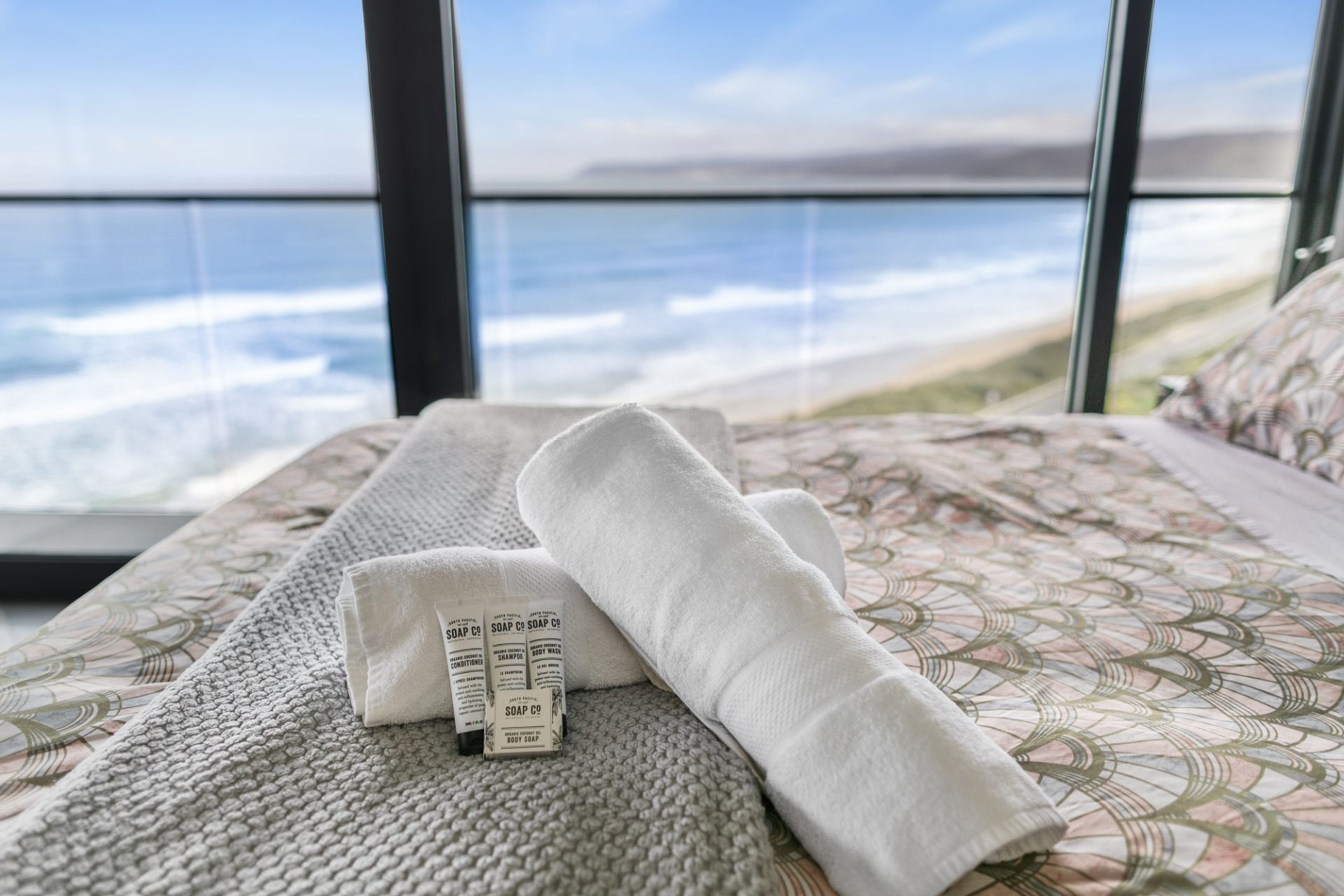 Ein Bett mit Meerblick, ein Handtuch und zwei Seifenflaschen.