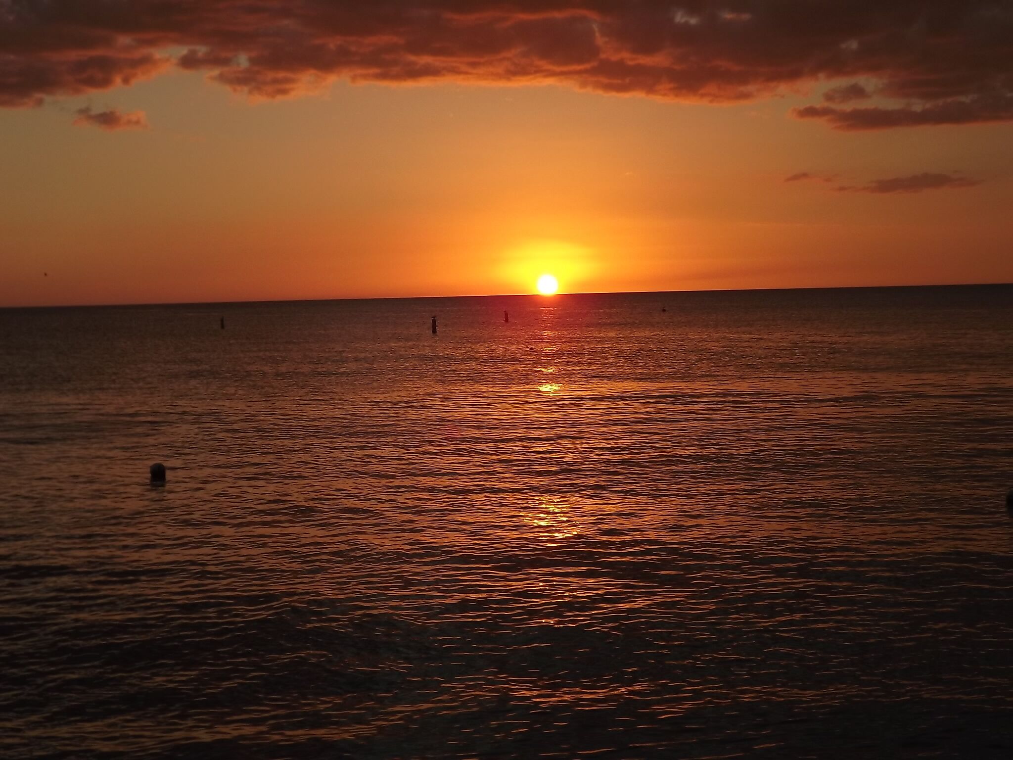Un coucher de soleil sur une mer calme, avec un horizon dégagé.