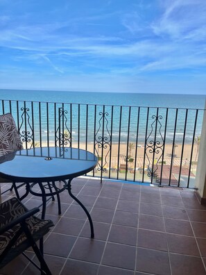 A balcony with a view of the sea, a round table, and a patterned chair. - Valencia: Beautiful Apartment in the beach  (Valencia)