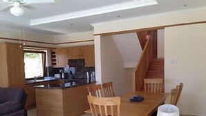 Une cuisine moderne avec des meubles en bois, un îlot central et un coin repas comprenant des chaises et une table en bois.