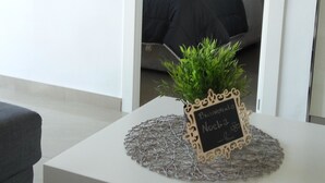 Un salon bien aménagé, avec une console blanche, une petite plante en pot et un panneau noir.
