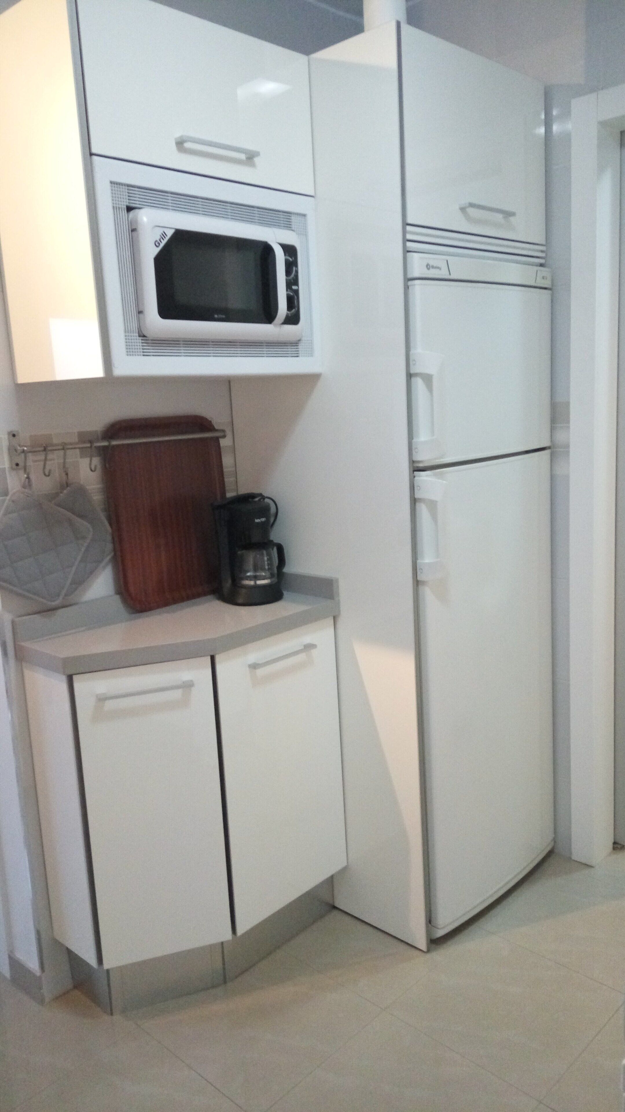 A compact kitchen with a microwave, a coffee maker, and a refrigerator.