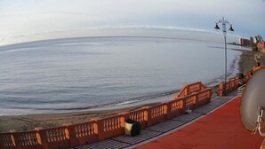 Une promenade en bord de mer avec un motif à carreaux, un tapis rouge et une rambarde ornée de balustres.