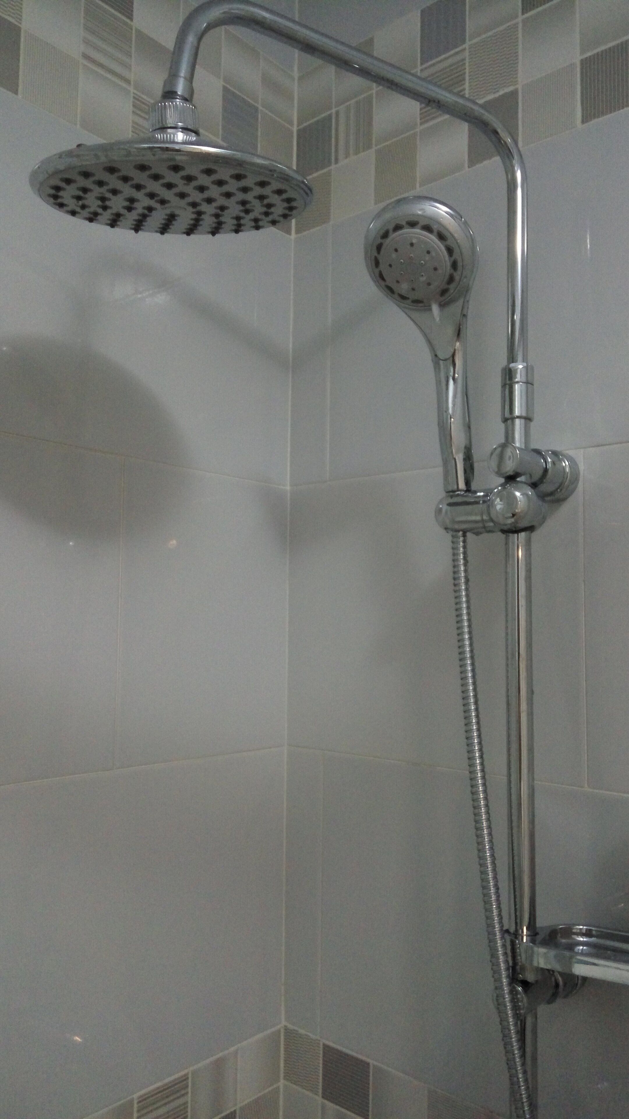 A shower with a handheld showerhead and a fixed wall-mounted showerhead.