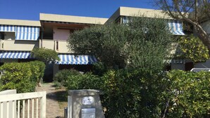 Un immeuble doté d’une entrée fermée par un portail, d’un auvent à rayures bleues et d’une enseigne indiquant « Villa Carrozzo ».