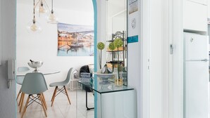 Una cocina moderna con una isla de vidrio, una zona de comedor con una silla y una mesa, y un refrigerador.
