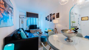 Una sala de estar moderna con sofá, televisión y comedor.
