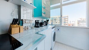 Una cocina moderna con lavadora, cafetera y bloque de cuchillos.