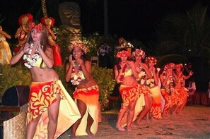 A group of people in traditional attire performing on a stage with a backdrop of tropical plants and a large statue. - World famous Over Water Bungalow on Bora Bora!! Marlon Brando's Bora Bora Home! (Vaitape)