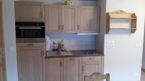 A compact kitchen with wooden cabinets, a built-in oven, and a small countertop. - Superb new apartment, nice and functional. Heartwarming welcome.  (Saint-Gervais-Les-Bains)