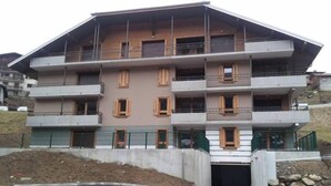 A multi-story residential building with balconies, a garage, and a fenced perimeter. - Superb new apartment, nice and functional. Heartwarming welcome.  (Saint-Gervais-Les-Bains)