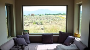 Una habitación con un gran ventanal que ofrece vistas a un paisaje desértico y montañas.