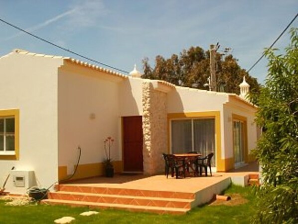 A two-story house with a patio, a dining area, and a small garden.