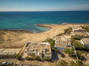 A coastal residential area with buildings, a beach, and the sea.