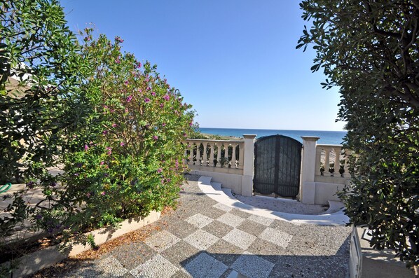 A paved pathway leading to a gate with a view of the sea.