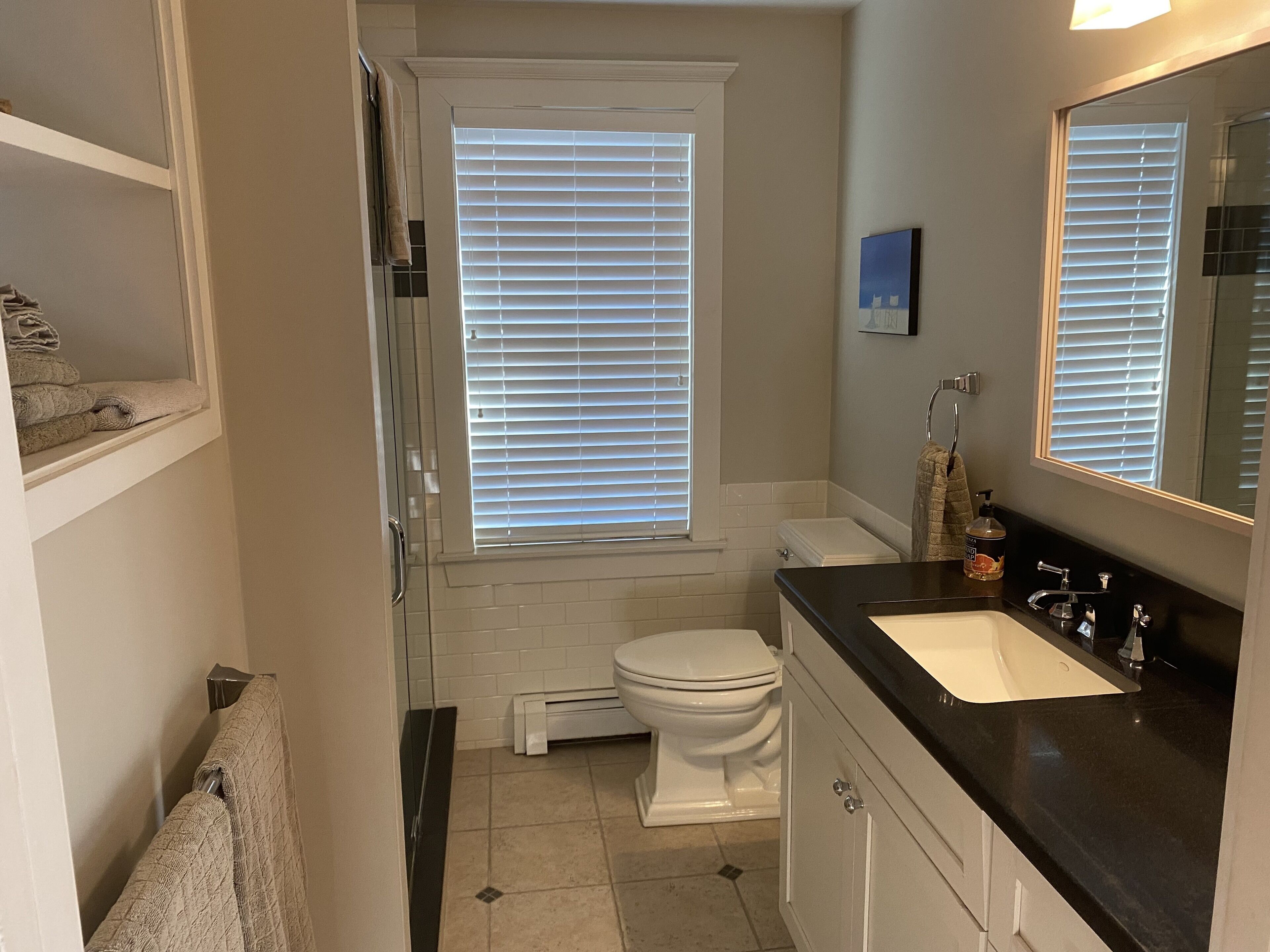 Een badkamer met toilet, wastafel en raam met zonwering.