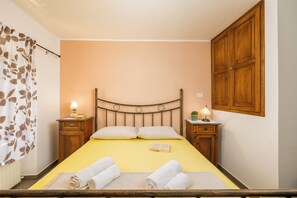 A bedroom with a bed, two bedside tables, a wooden wardrobe, and a curtain with a leaf pattern. - Authentic Istrian House - Family Apartment with saltwater pool - near Kamenjak (Pula)