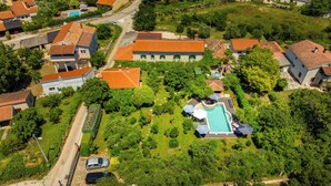 Vue aérienne d’un quartier résidentiel avec une piscine entourée d’une végétation luxuriante et de maisons aux toits recouverts de tuiles rouges.