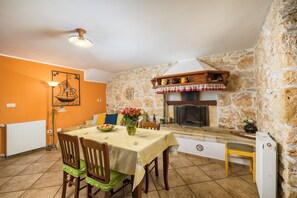 A dining area with a stone wall, a fireplace, and a table set with a vase of flowers.