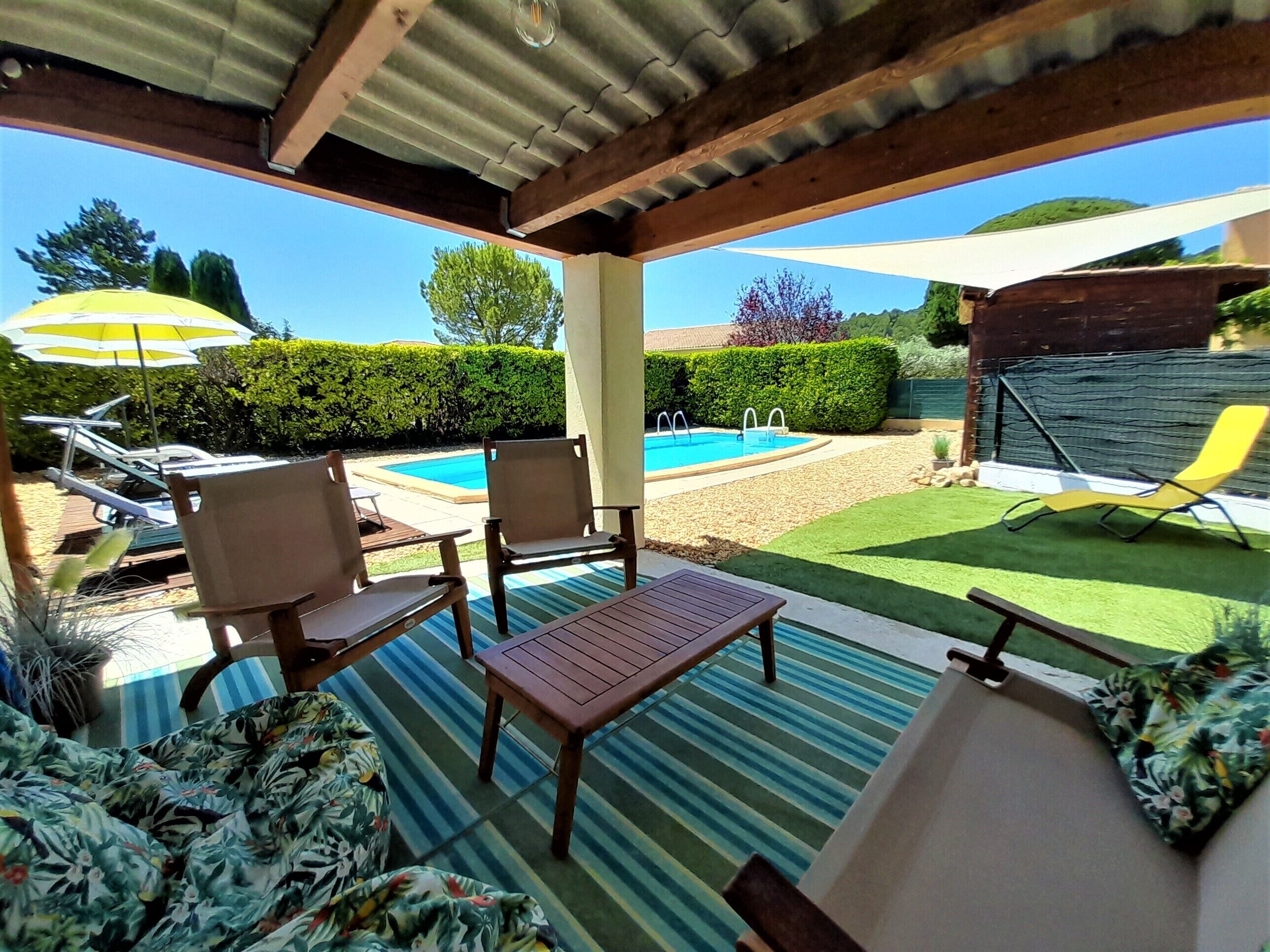 Un patio cubierto con piscina, sillas de descanso y una mesa.