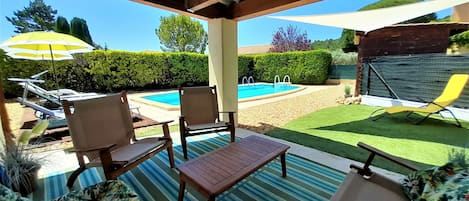 Un patio cubierto con piscina, sillas de descanso y una mesa.