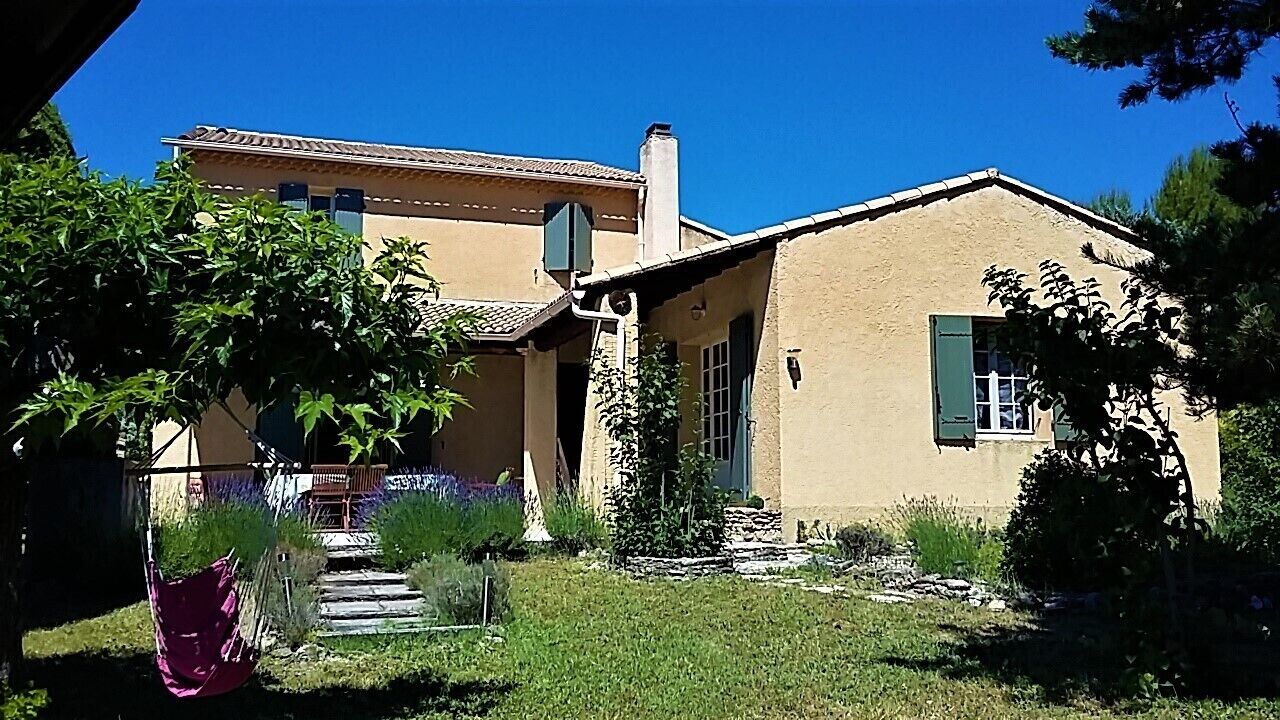 Une maison à deux étages, avec un toit en tuiles, une cheminée et un petit porche.