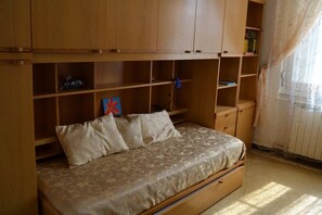 A bedroom with a bed, wooden cabinets, and a window with curtains. - Quiet apartment surrounded by the green and very close to the sea (Sestri Levante)