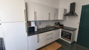 Een kleine keuken met witte kastjes, een magnetron, een spoelbak en een fornuis.