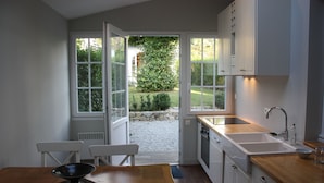 A modern kitchen with white cabinets, a wooden countertop, and a large window.