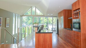 A modern kitchen with wooden cabinets, stainless steel appliances, and a large island. - THE GLASS PINNACLE : Bright (Bright)