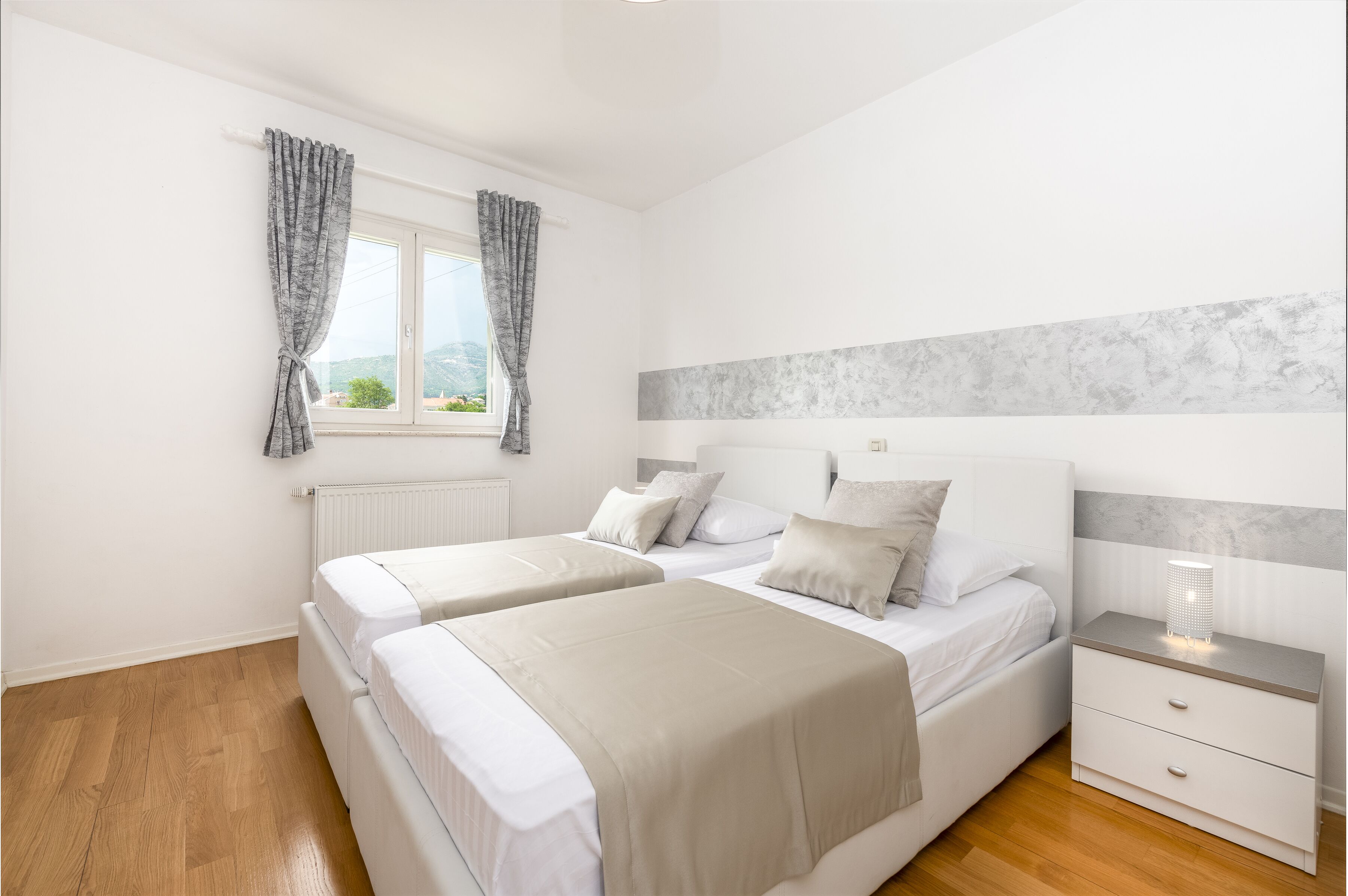 Un dormitorio con dos camas, una mesita de noche y una ventana con cortinas.