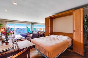 Une chambre d’hôtel avec un lit, un bureau, une chaise et une vue sur la mer.