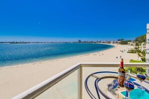A balcony with a view of a beach, a pool, and a bottle of wine. - Bayfront Balcony, beach access, parking, bikes (San Diego)
