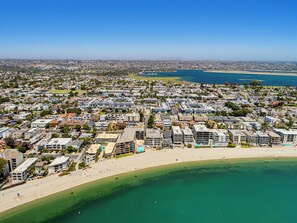 A coastal cityscape with a beachfront, residential buildings, and a clear blue sky.