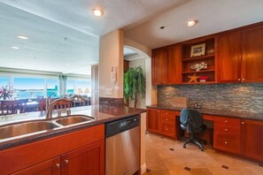A modern kitchen with a dishwasher, wooden cabinets, and a view of the outdoors. - Bayfront Balcony, beach access, parking, bikes (San Diego)
