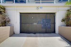 A gated entrance with a metal gate, a sign indicating video surveillance, and a concrete pathway leading to the gate. - Bayfront Balcony, beach access, parking, bikes (San Diego)