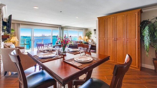 A dining area with a view of the sea, wooden furniture, and a large cabinet. - Bayfront Balcony, beach access, parking, bikes (San Diego)