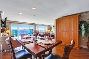 A dining area with a view of the sea, wooden furniture, and a large cabinet. - Bayfront Balcony, beach access, parking, bikes (San Diego)