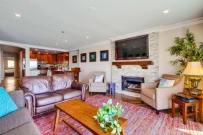 A living room with a fireplace, leather sofas, a coffee table, and a TV mounted above the fireplace.