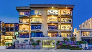 A multi-story hotel with balconies, a gated entrance, and outdoor plants. - Bayfront Balcony, beach access, parking, bikes (San Diego)