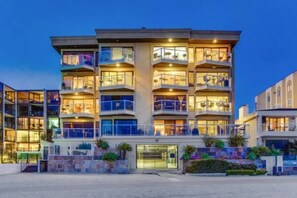 Et hotel med flere etager, altaner, en lukket indgang og udendørs beplantning.