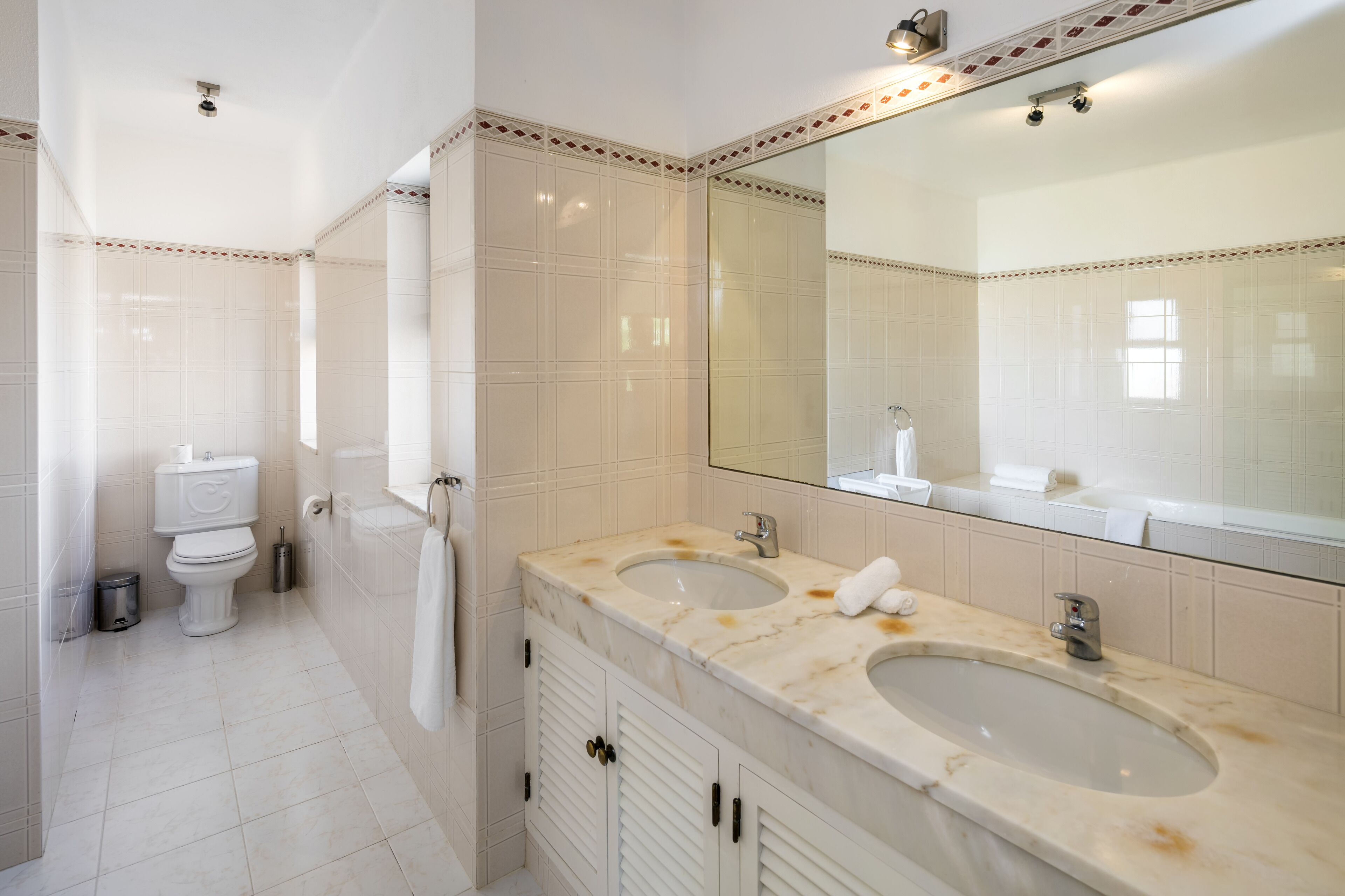 Een badkamer met twee wasbakken, een toilet en een grote spiegel.